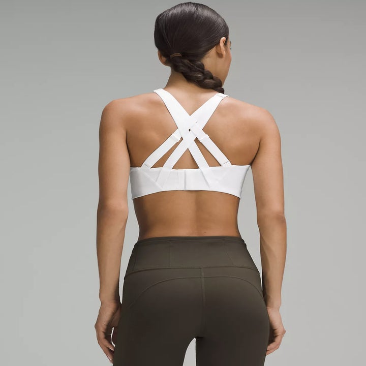 model wearing a white strappy sports bra and high-waisted leggings, facing away, showcasing the back design