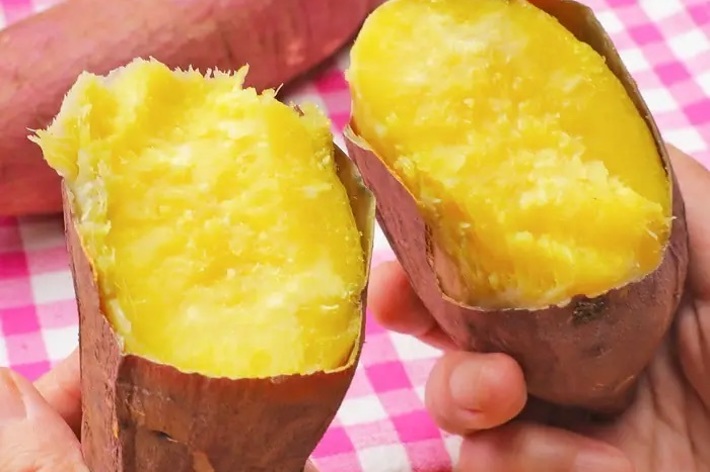 手で割った焼き芋がピンクのチェックの布の上に置かれている。