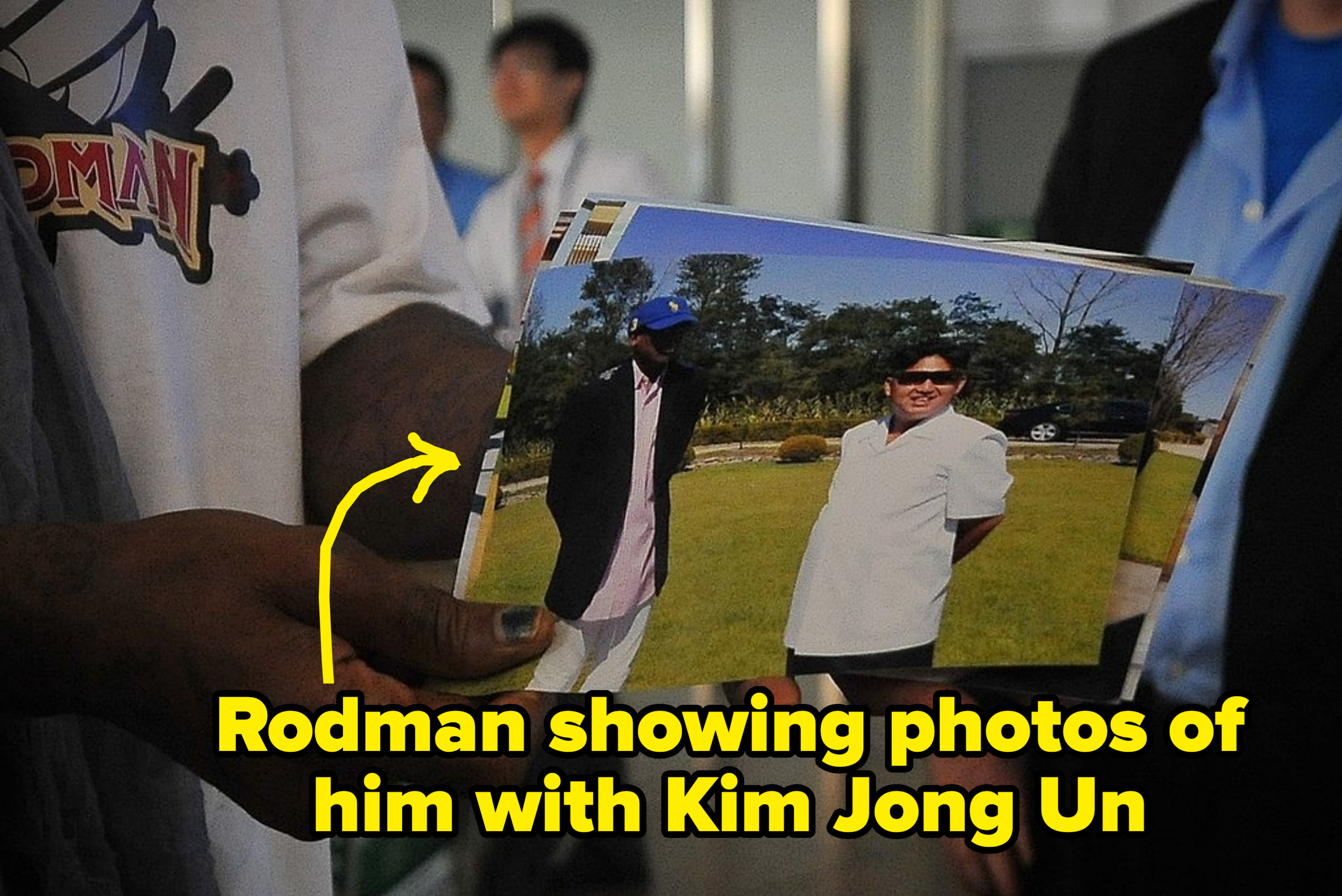 A idiosyncratic   is holding a photograph  of 2  individuals lasting  extracurricular  successful  a grassy country  with trees successful  the background