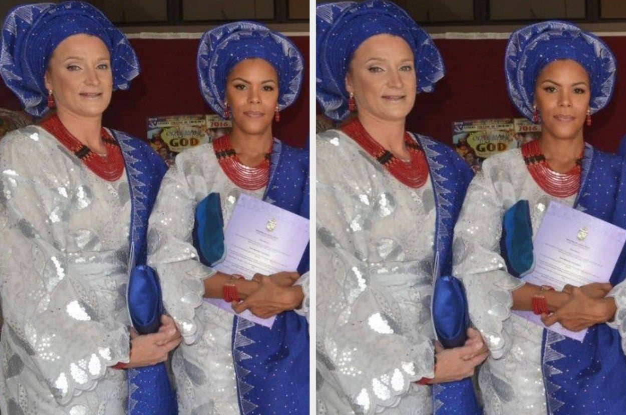 Two people wearing elaborate traditional attire with headpieces and jewelry, holding a booklet, possibly at a cultural or formal event