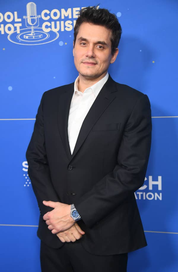 Person in a sleek suit poses in front of a backdrop at an event