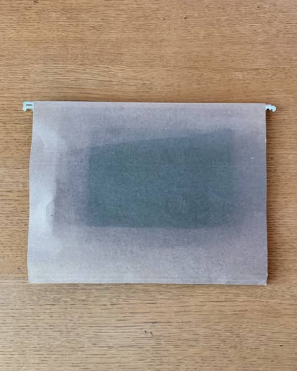 Translucent parchment covers a dark rectangular object on a wooden table
