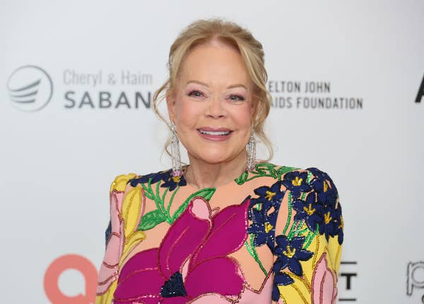 Person smiling, wearing a floral-patterned dress with intricate embroidery at an event