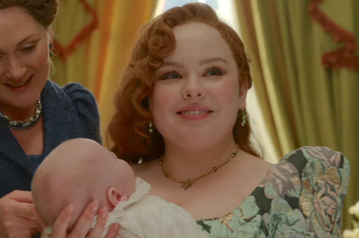Penelope from Bridgerton smiling and holding a baby