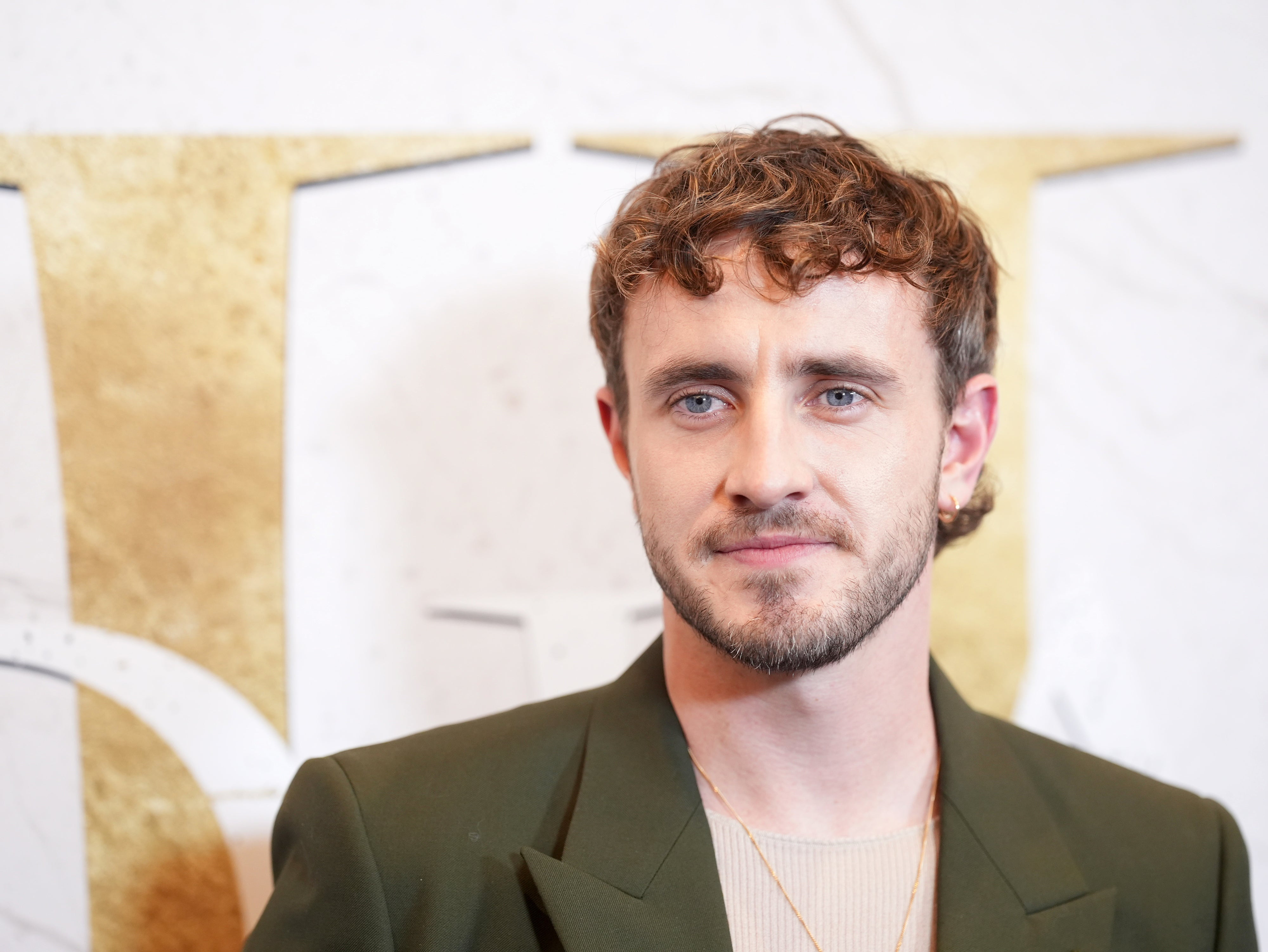 Paul Mescal in a green blazer and light shirt poses for a photo at an event