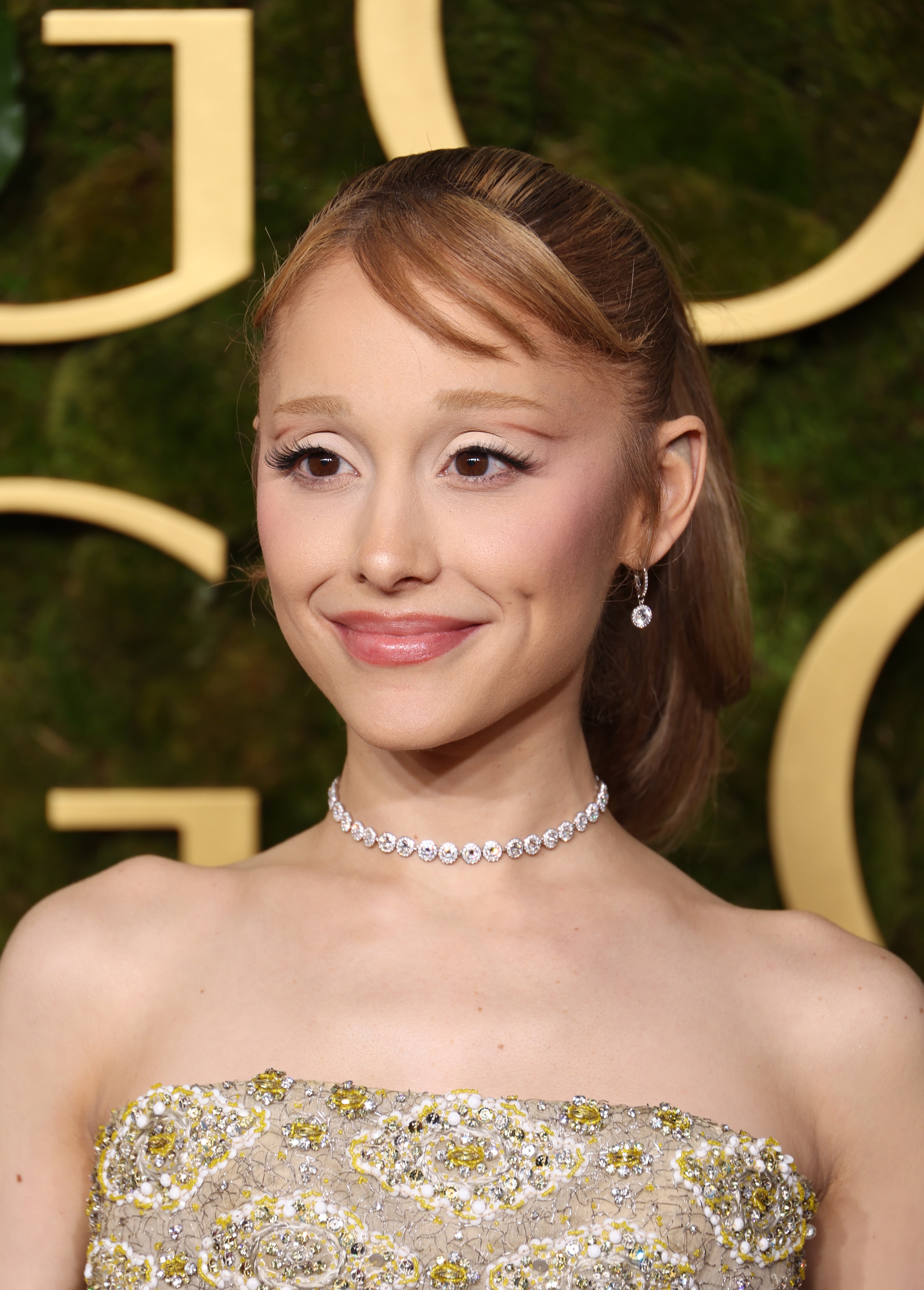 Ariana Grande in elegant strapless gown with intricate detailing, wearing drop earrings and a diamond choker, on a red carpet event