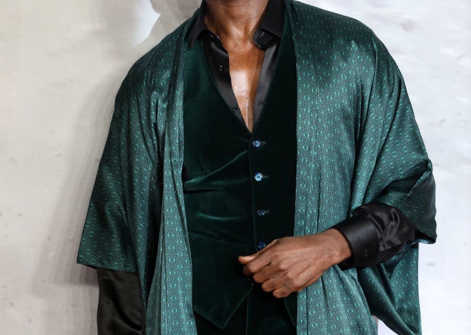 Person on red carpet wearing a stylish, dark velvet suit with a matching long robe