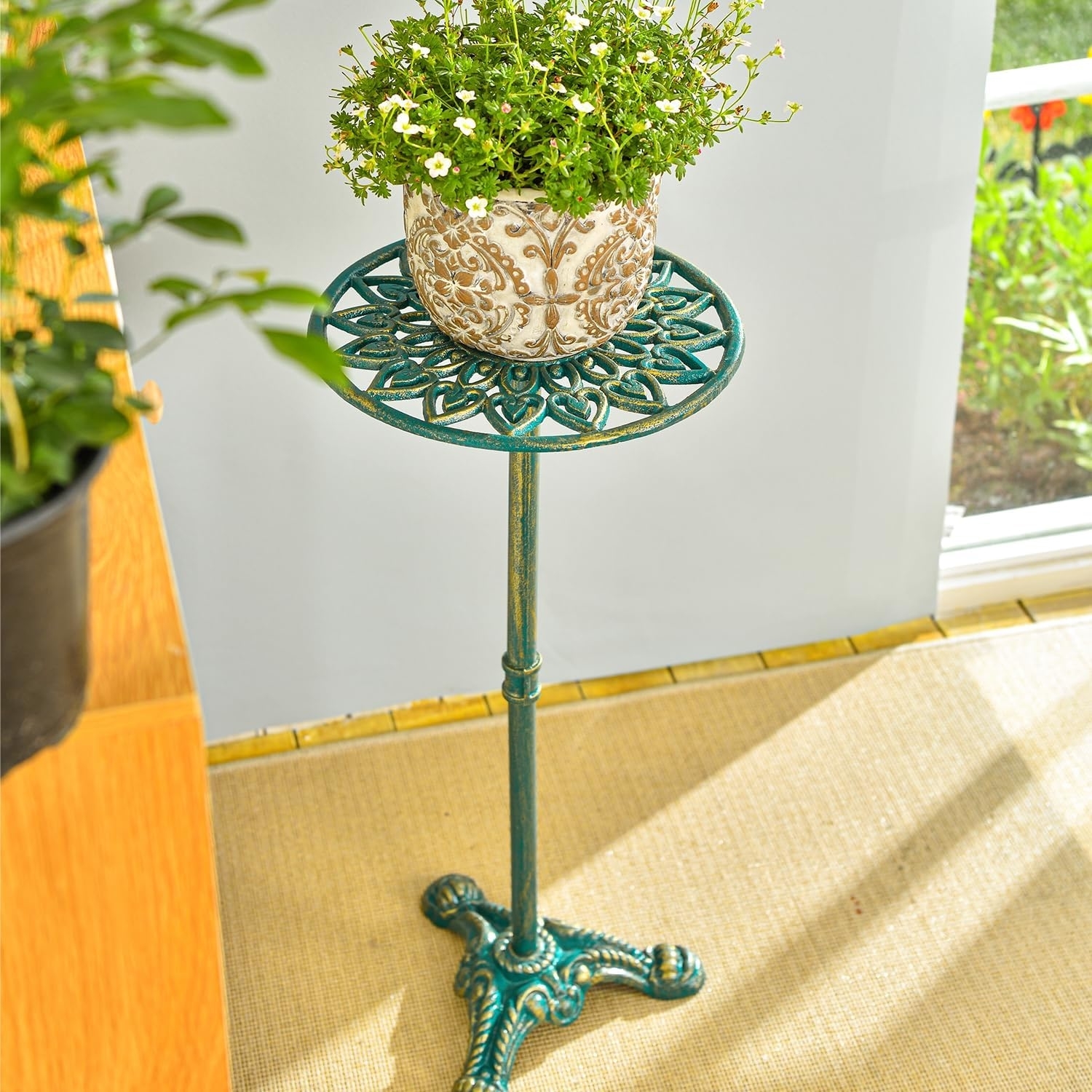 Plant with small white flowers in a decorative pot on an ornate metal stand in a sunlit room