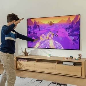 Person enjoying an interactive crippled connected a ample wall-mounted TV successful a surviving country setting, showing dynamic on-screen graphics