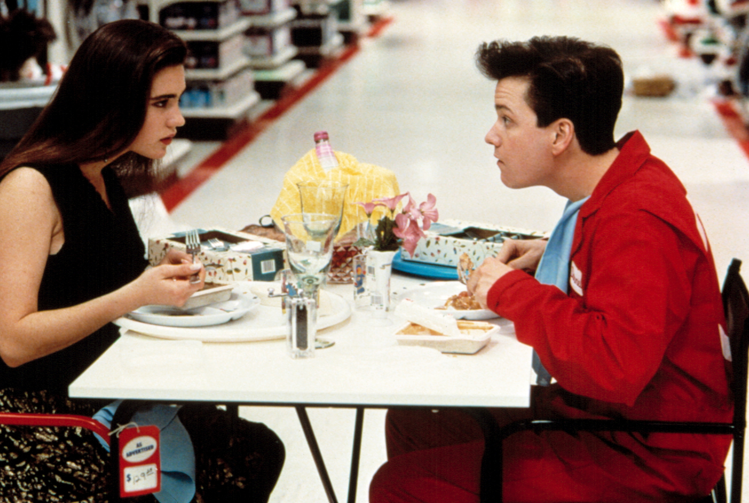 Jennifer Connelly and Frank Whaley sit at a table in the Target food court in "Career Opportunities"