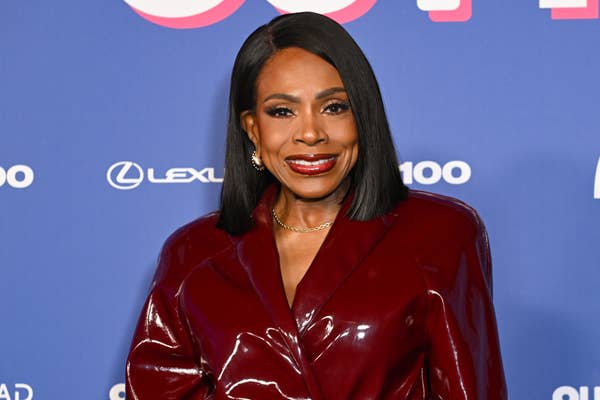Sheryl Lee Ralph smiling on the red carpet, wearing a shiny, elegant coat with sleek styling