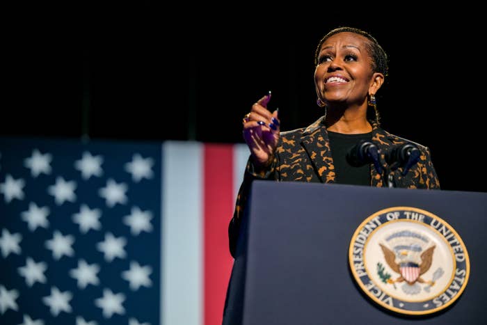 A person speaks at a podium with the U.S. presidential seal, set against a backdrop of the American flag