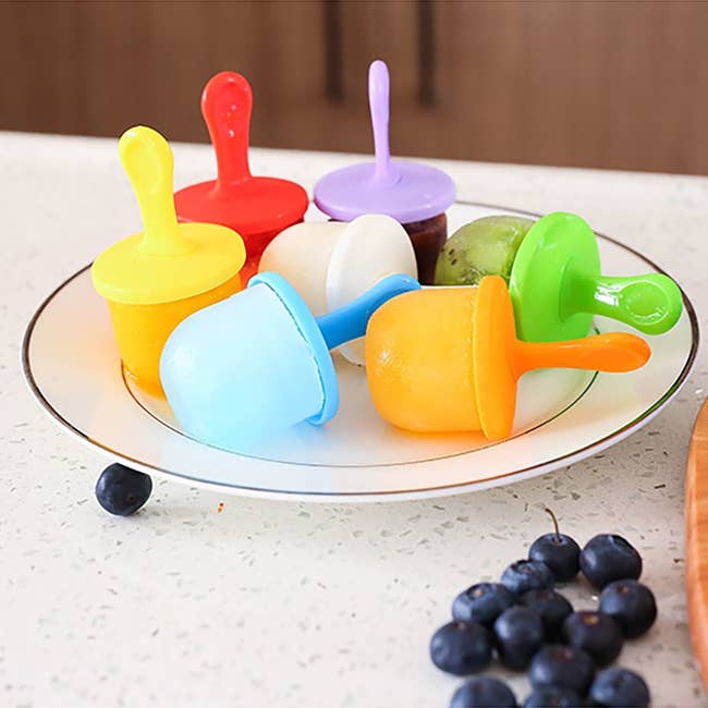Colorful popsicles with handles connected a plate, surrounded by caller blueberries; featured successful a buying article