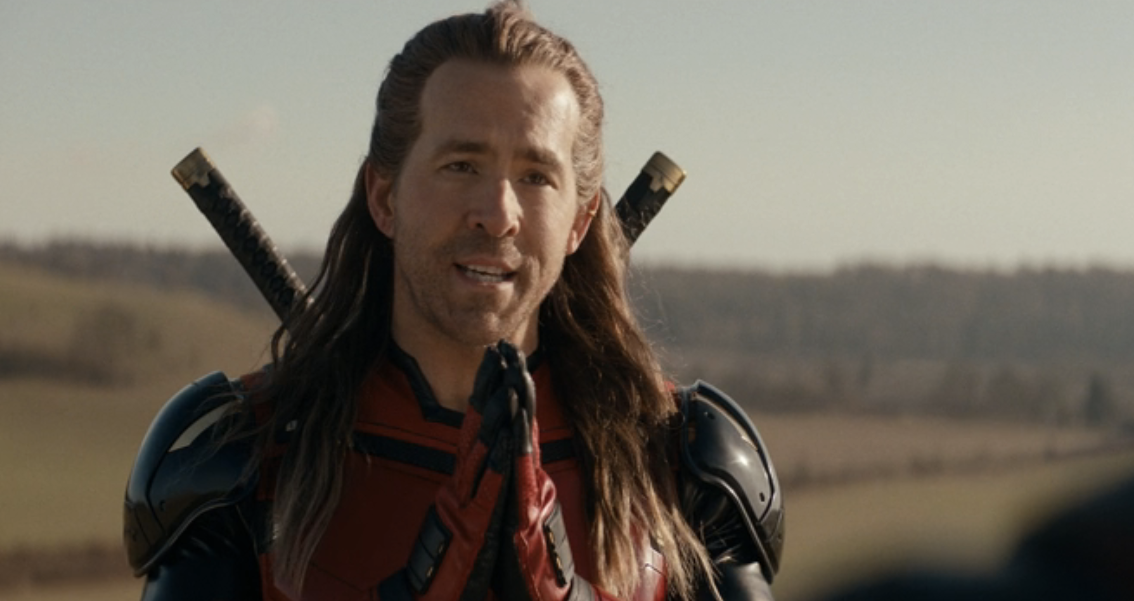 Person wearing armor with swords on their back, talking outdoors in a rural setting