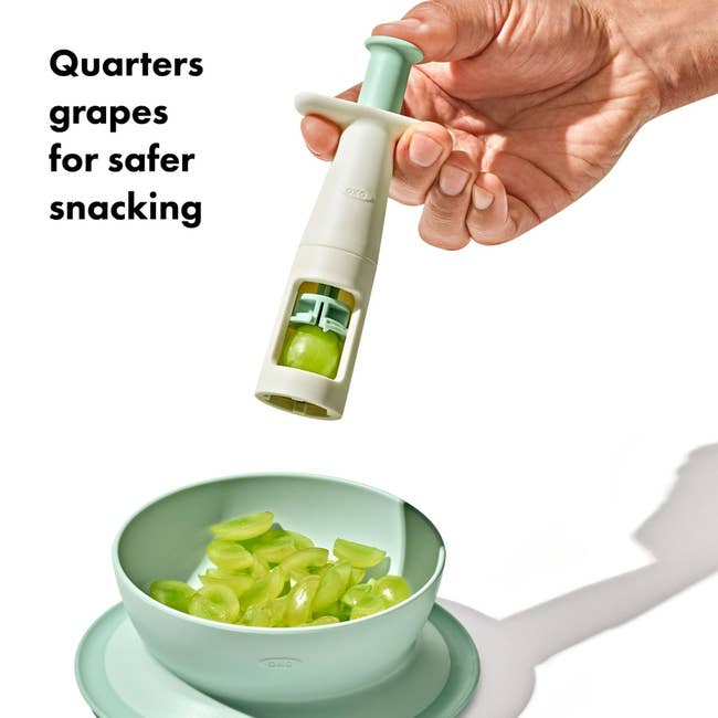 Hand utilizing a grape slicer to chopped grapes into quarters implicit a vessel for safer snacking