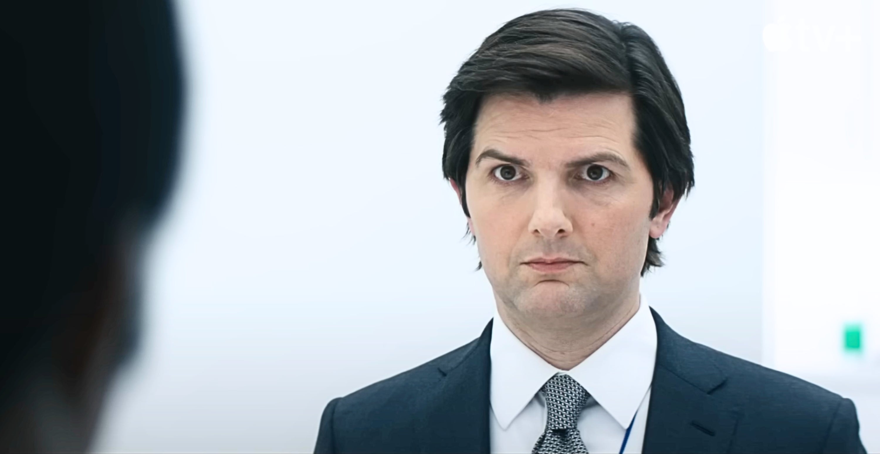 Person in a suit looks intently forward in a well-lit room
