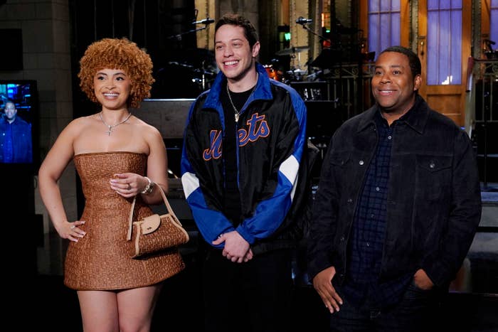 Three individuals on a set; person on the left in a strapless textured dress; middle in a sporty jacket; right in a casual jacket, all smiling