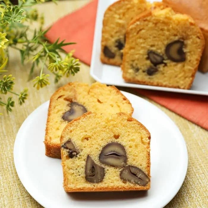 プレートの上にカットされたマロン入りのパウンドケーキ。背景に黄色の花とナプキン。