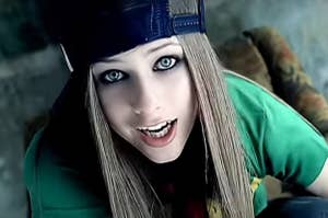 Person wearing a backward cap and a casual green shirt, looking up at the camera with parted lips