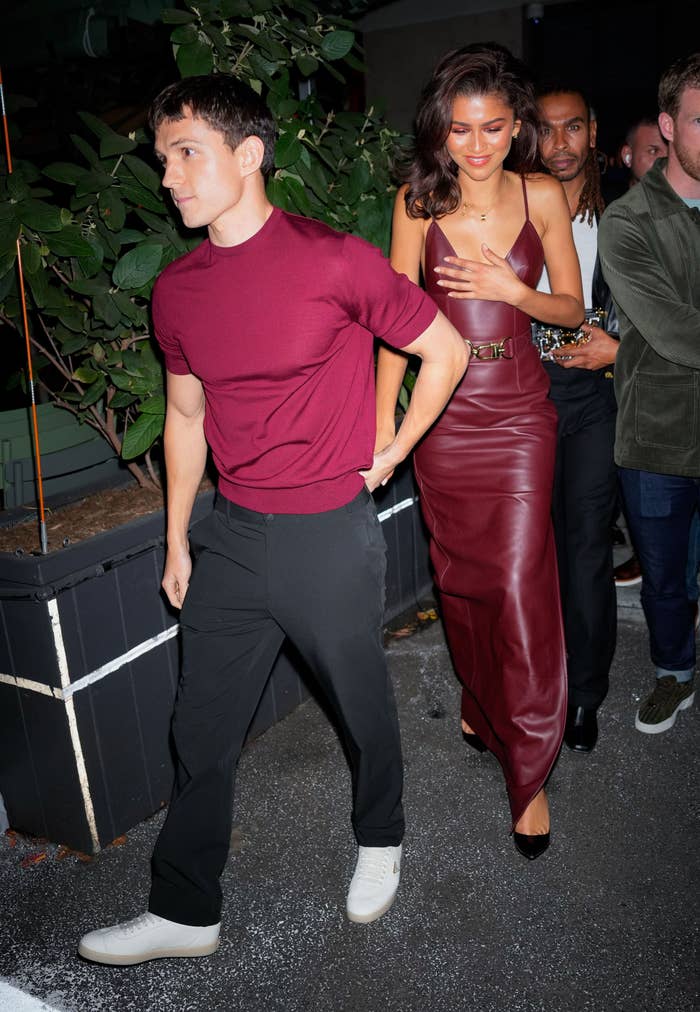 Tom Holland and Zendaya are walking outside of an event