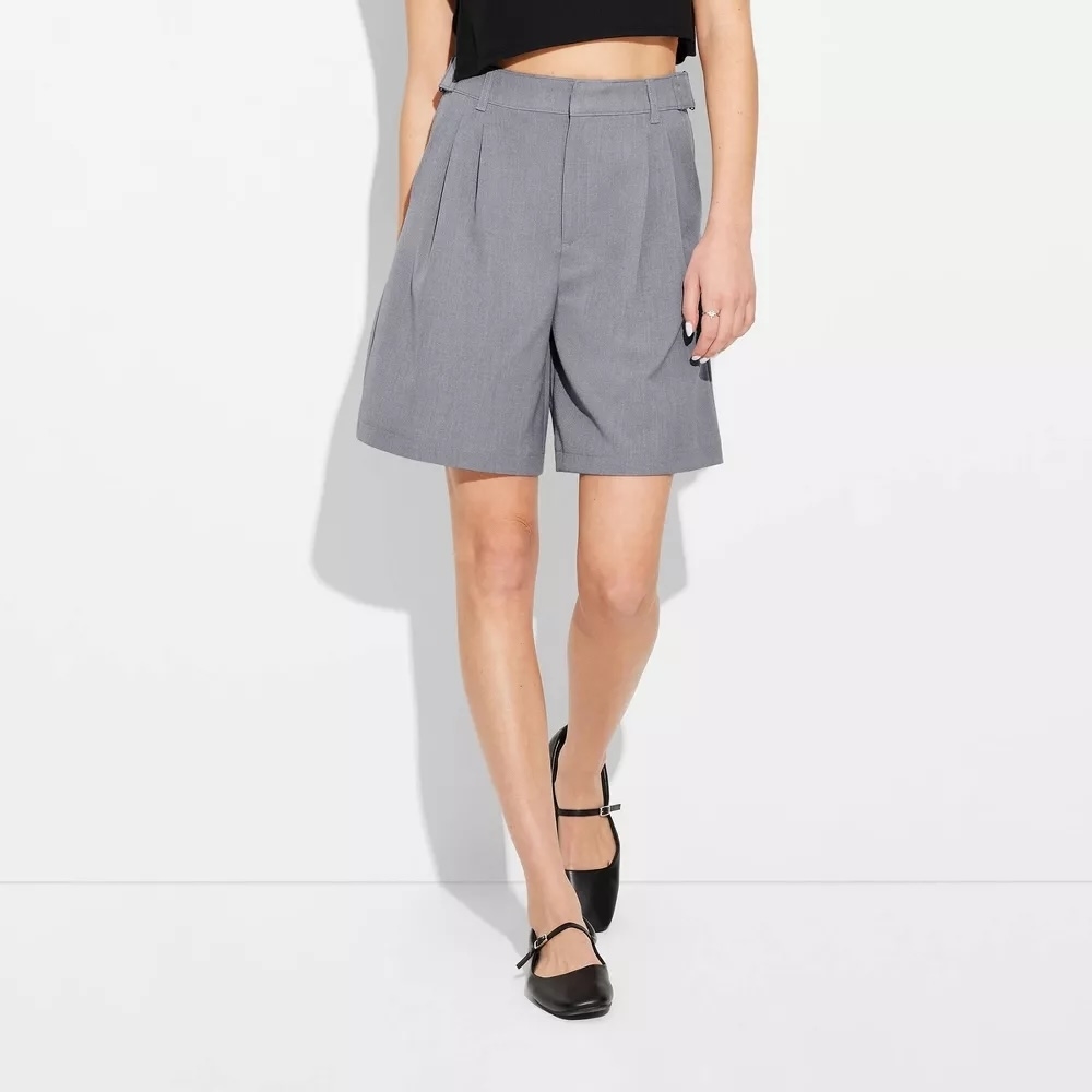 Person wearing knee-length tailored shorts and strappy flats, suitable for a modern, casual look