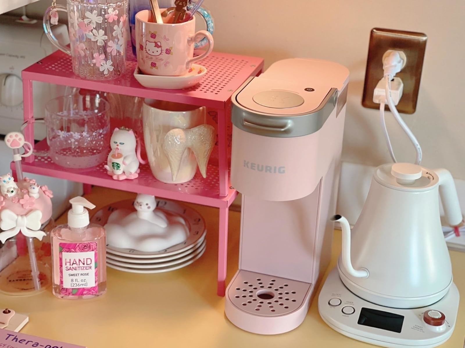 Coffee presumption    with a pinkish  Keurig, achromatic  electrical  kettle, mugs, and manus  sanitizer
