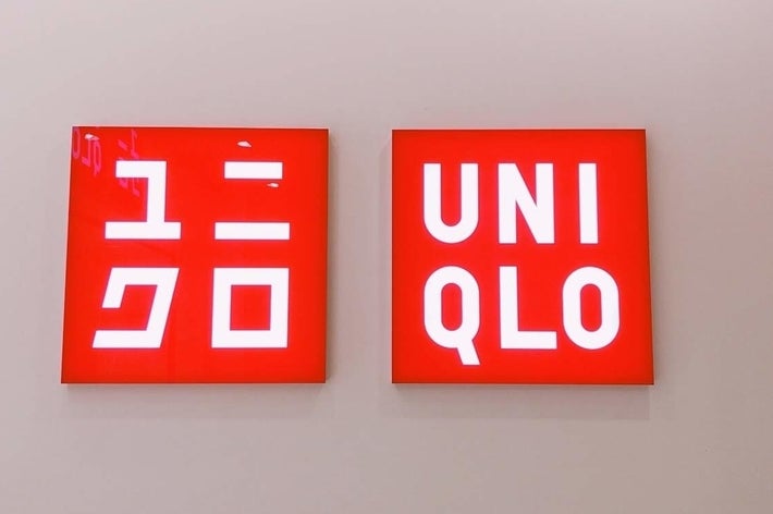 Two red and white signs showing &ldquo;Uniqlo&rdquo; in English and Japanese Katakana
