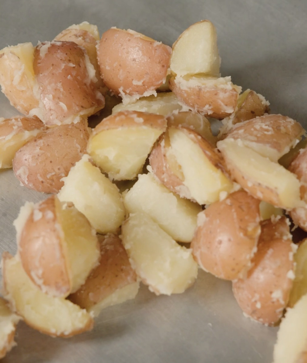 Boiled babe  potatoes with tegument  on, chopped  into halves and scattered connected  a metallic  surface