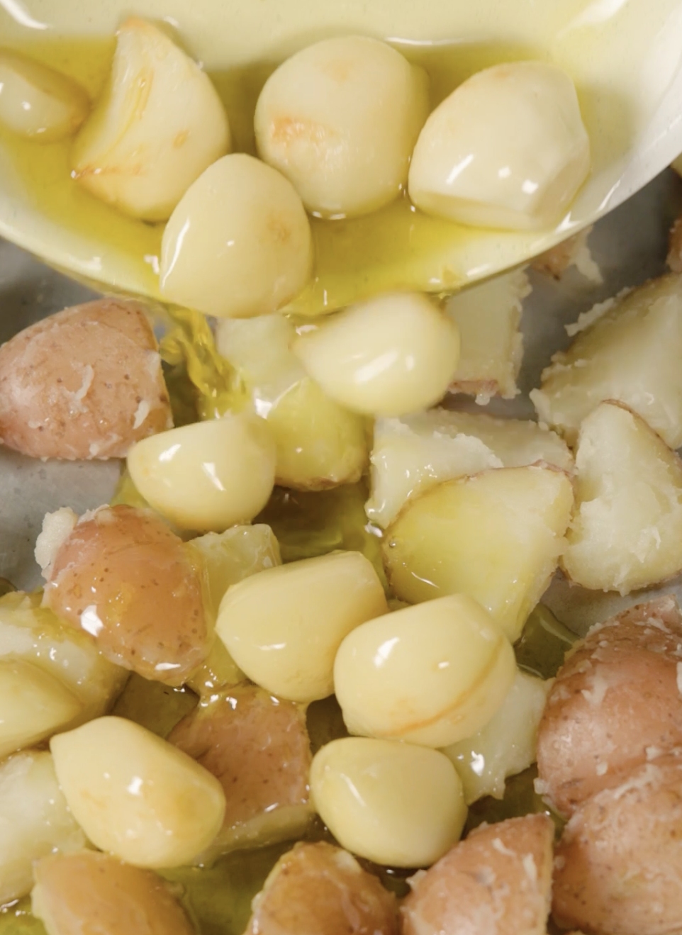 Garlic cloves and halved babe  potatoes successful  a crockery  being coated with olive oil