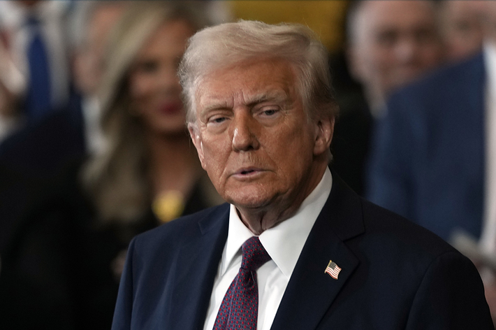 スーツを着た人が聴衆の前で立っている。周囲には拍手する人々がいる。