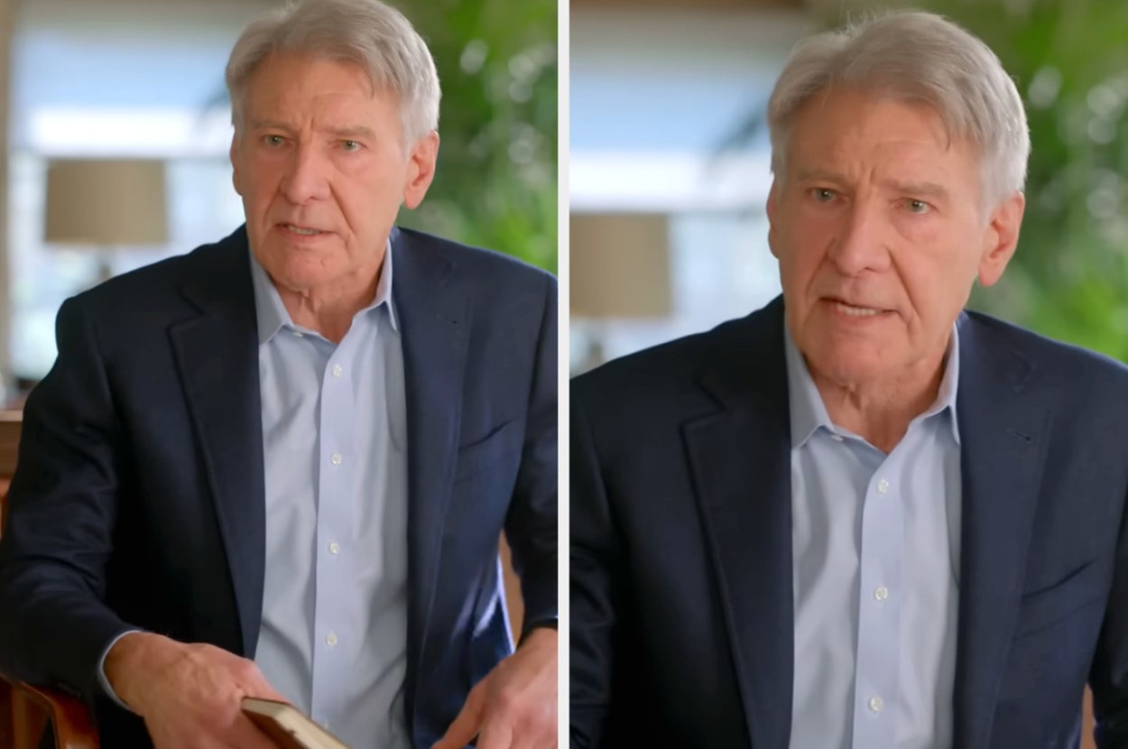 Harrison Ford in a suit and open-collared shirt sits indoors holding a book, expressing focus and engagement