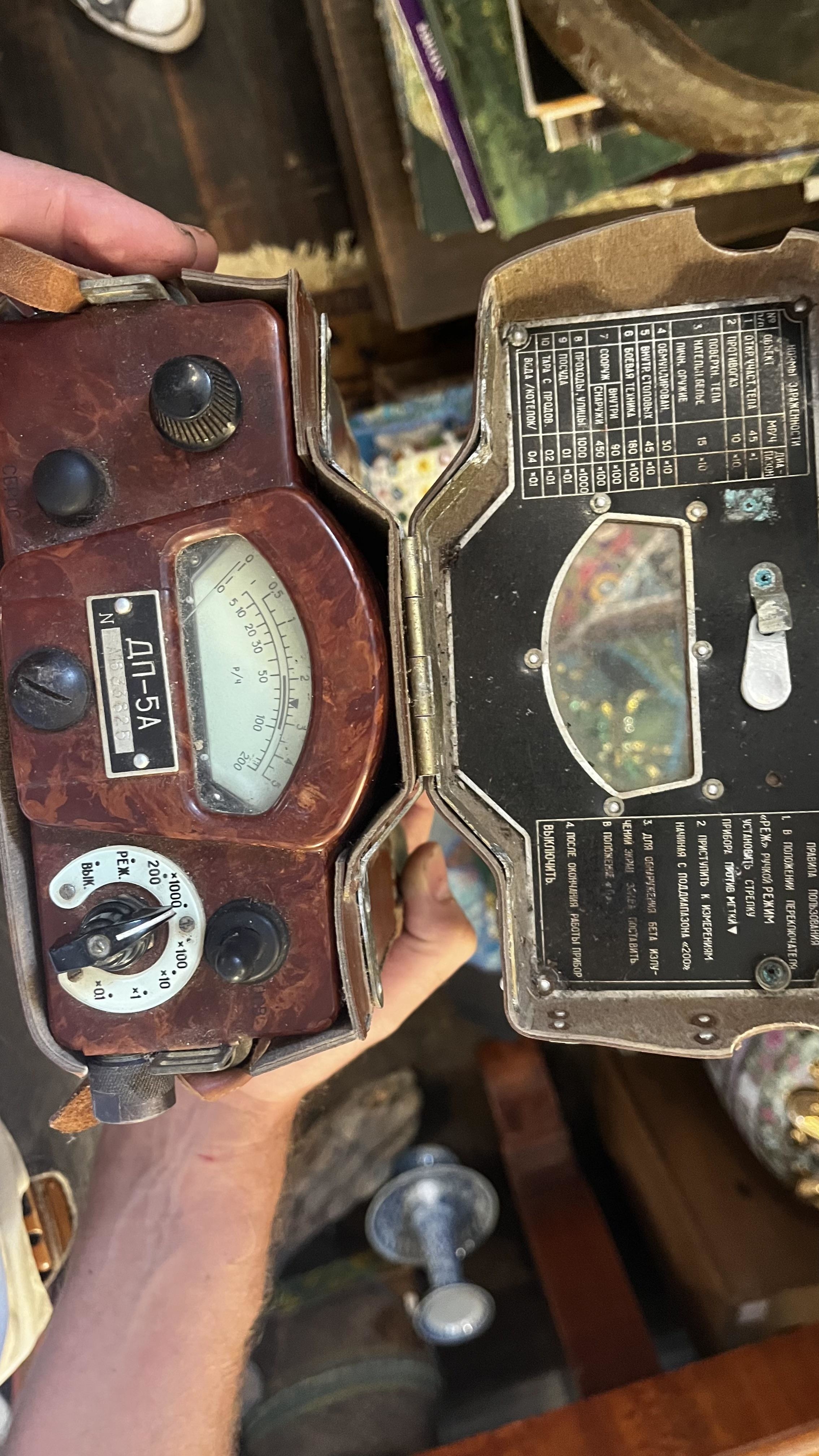Person holding a vintage Geiger counter with dials and a meter