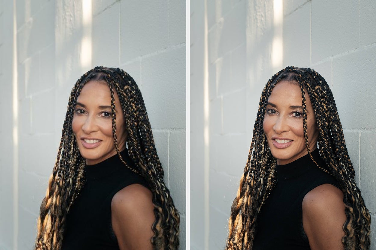 Person with long braided hair, wearing a sleeveless black top, smiling at the camera in an outdoor setting with a textured wall background