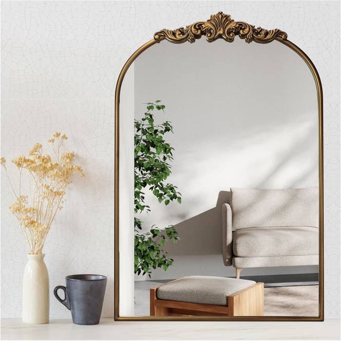 Elegant reflector with ornate framework reflecting a cozy surviving abstraction with a chair, plant, and brushed lighting