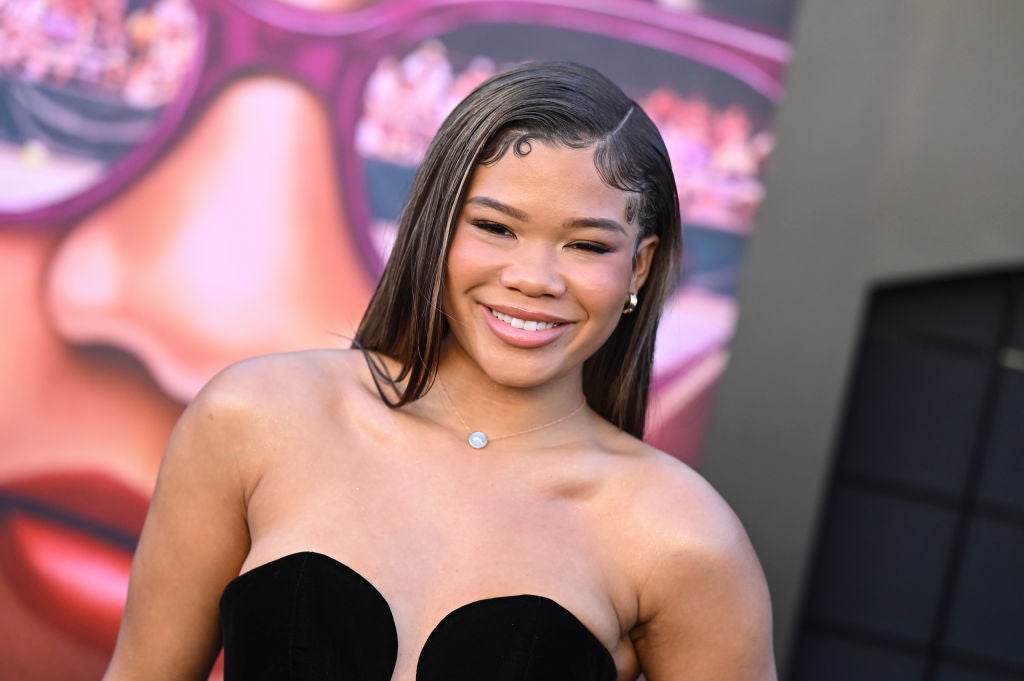 Person in strapless black dress smiling at a celebrity event