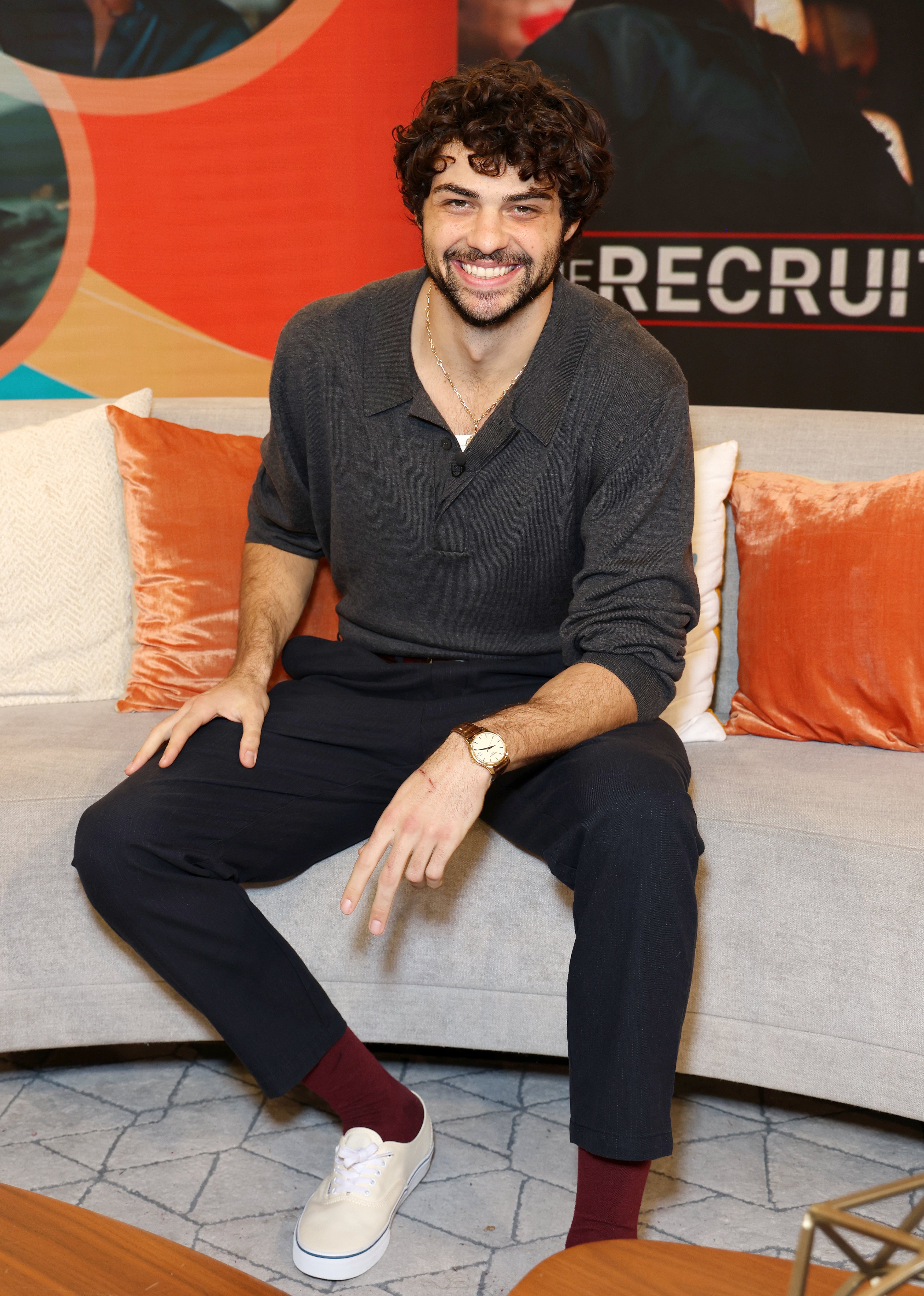 Noah Centineo sitting on a couch.