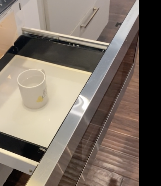 Open drawer with a built-in microwave below a countertop. Cup placed inside microwave. Reddit post titled "Microwave drawer."