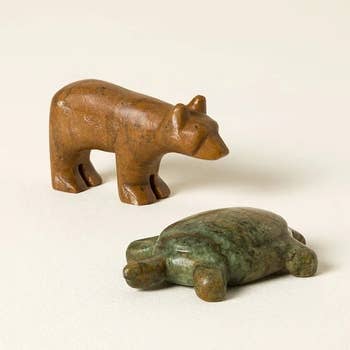 Wooden carnal figurines, 1 lasting bear, 1 resting turtle, displayed connected a neutral background