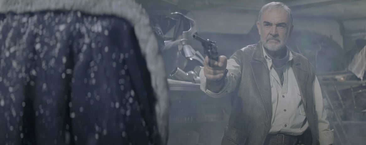 Man in rugged clothes points a revolver in a tense, snowy setting, facing someone with a fur-trimmed jacket seen from behind