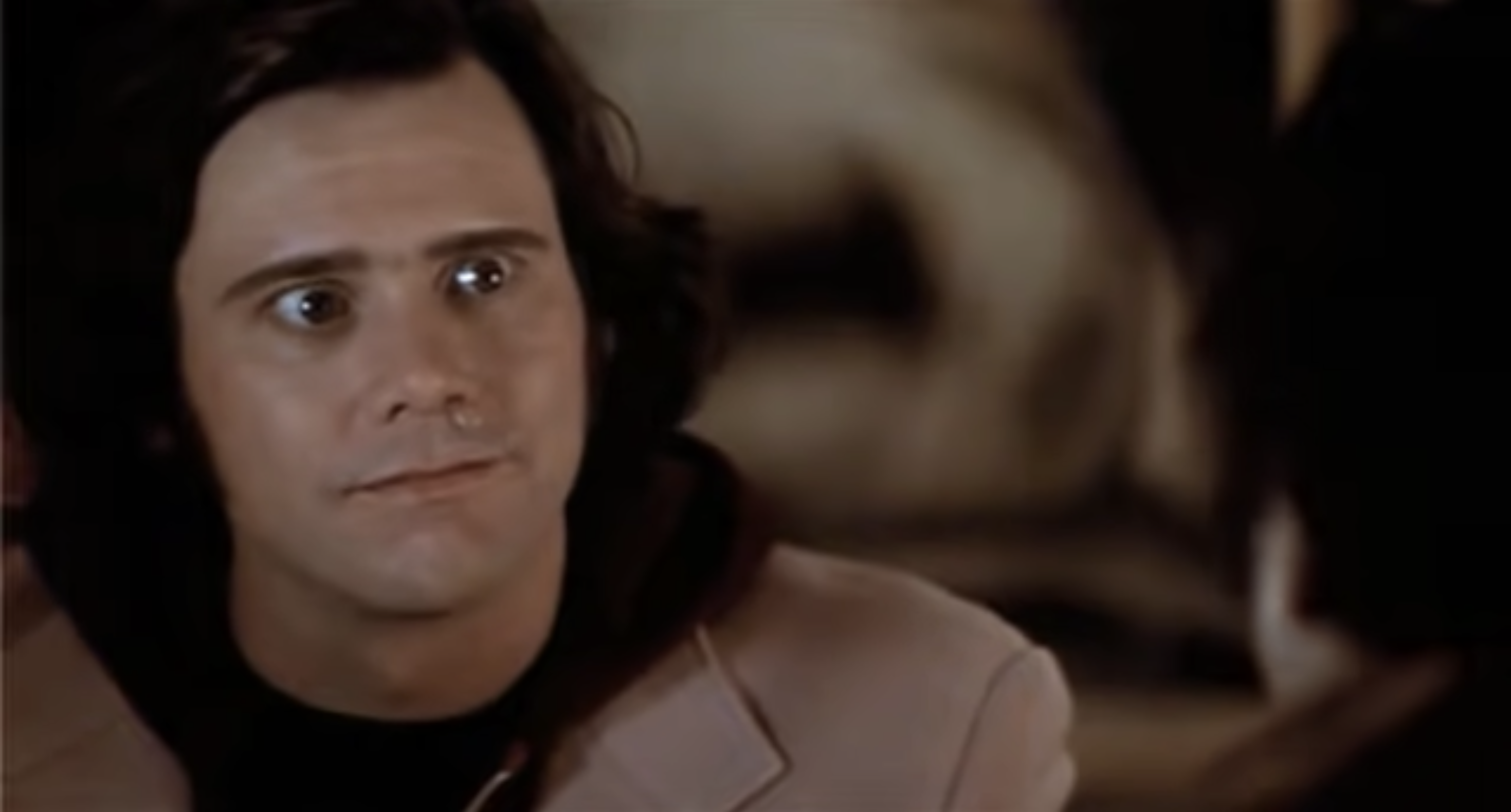 A person with medium-length hair looks intently to the side, wearing a jacket. The background is softly blurred