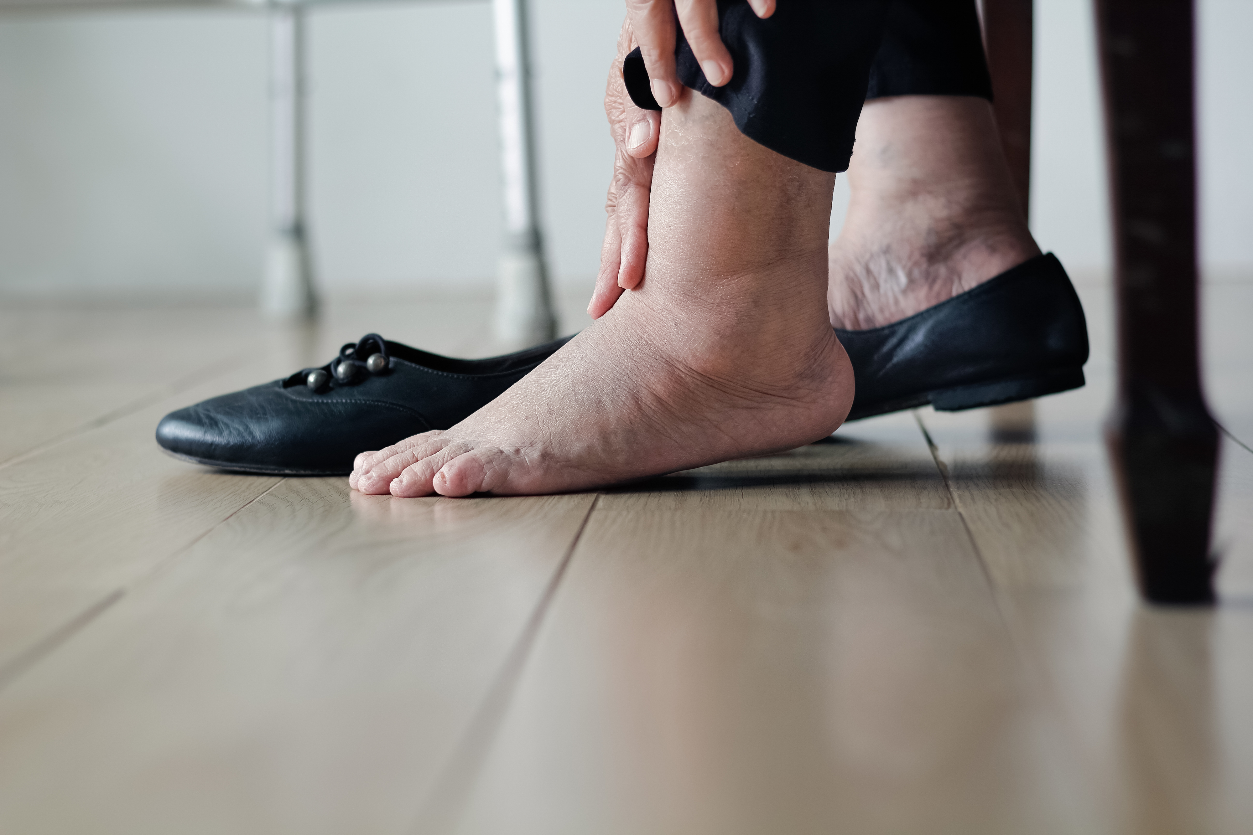 Person som masserer sin hovne ankel mens du har på seg en sko, fremhever potensielt ubehag eller avlastningsteknikker