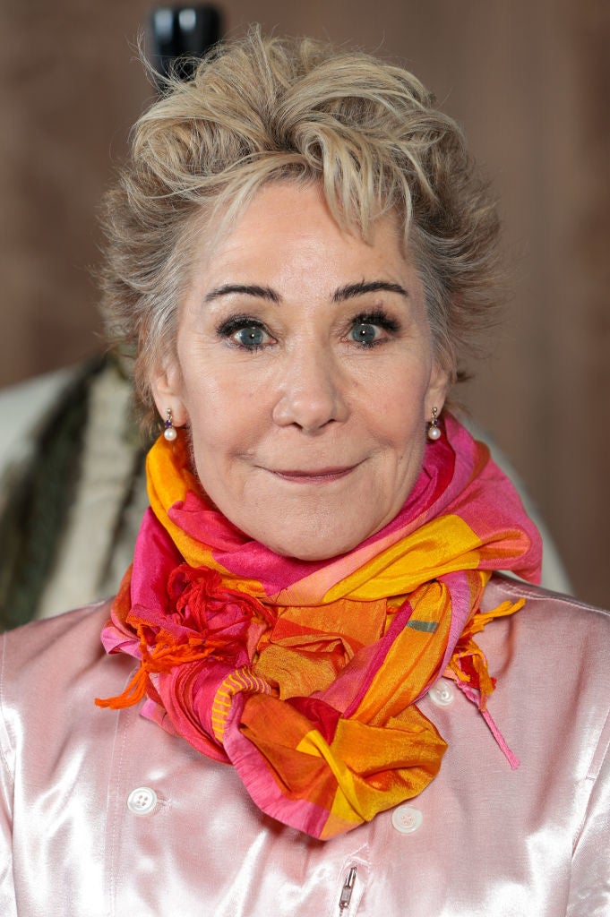 Zoë  with short hair wearing a colorful scarf and a jacket