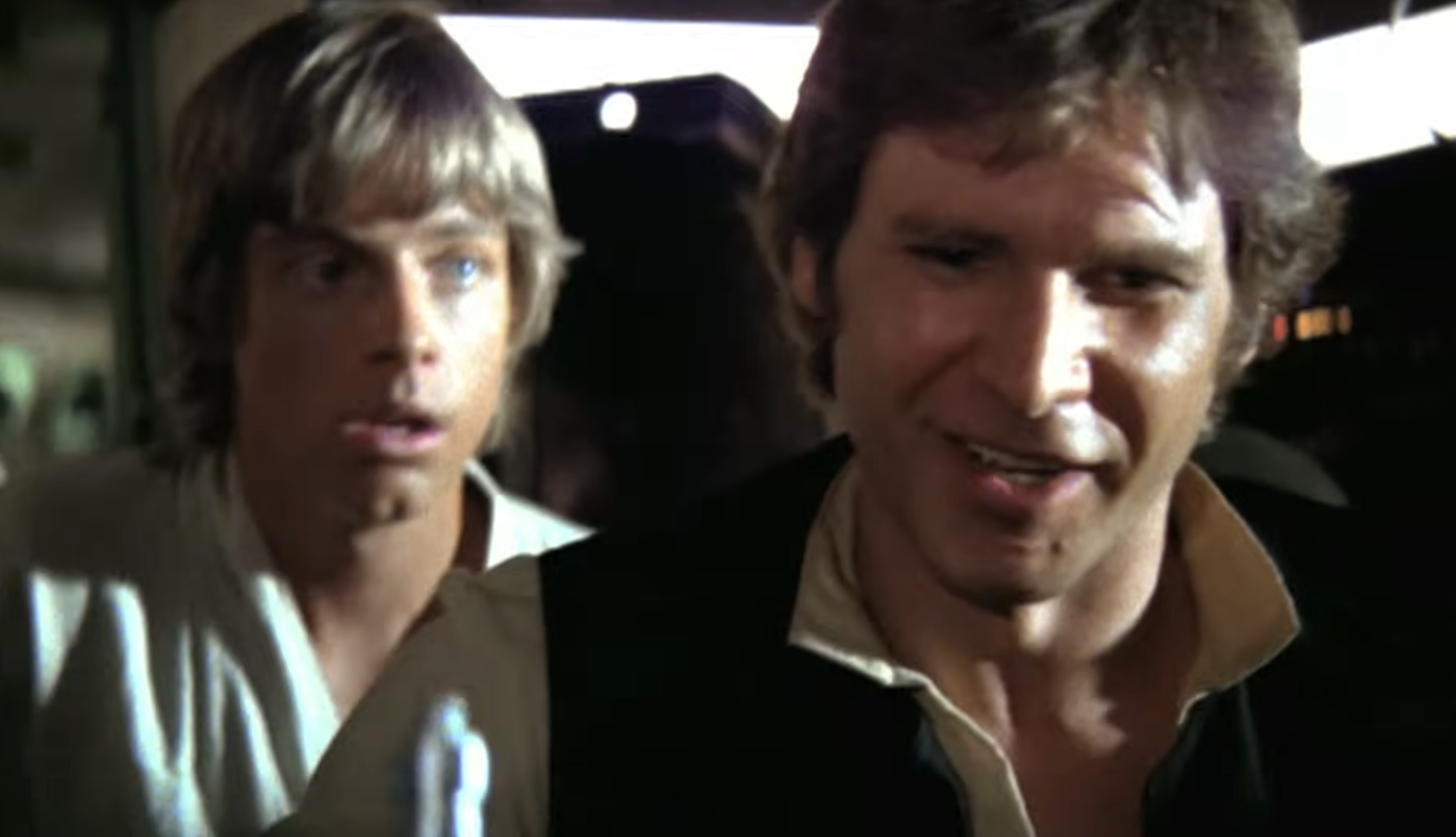 Two men in a sci-fi setting, one in a white shirt looking surprised and the other, smiling, in a black vest and white shirt