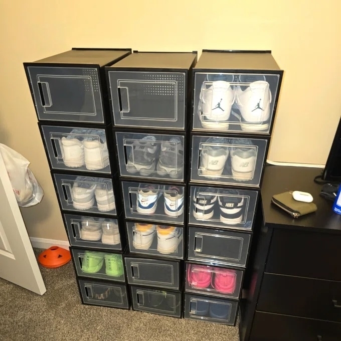 Stacked clear shoe storage boxes displaying various sneakers in a room