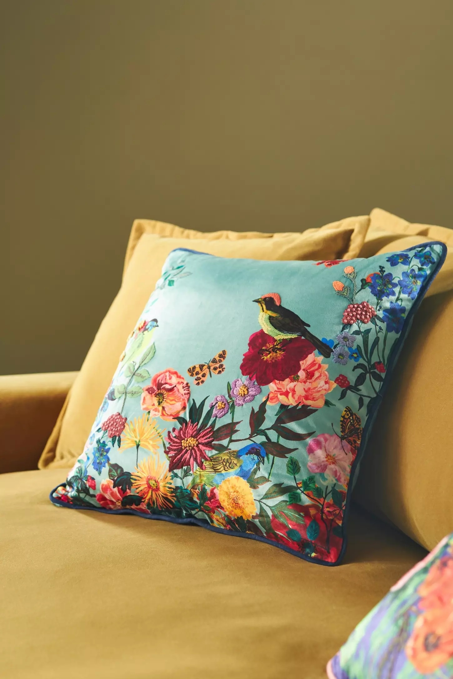 Floral pillow with a bird design on a beige sofa, highlighting vibrant decorative home accents