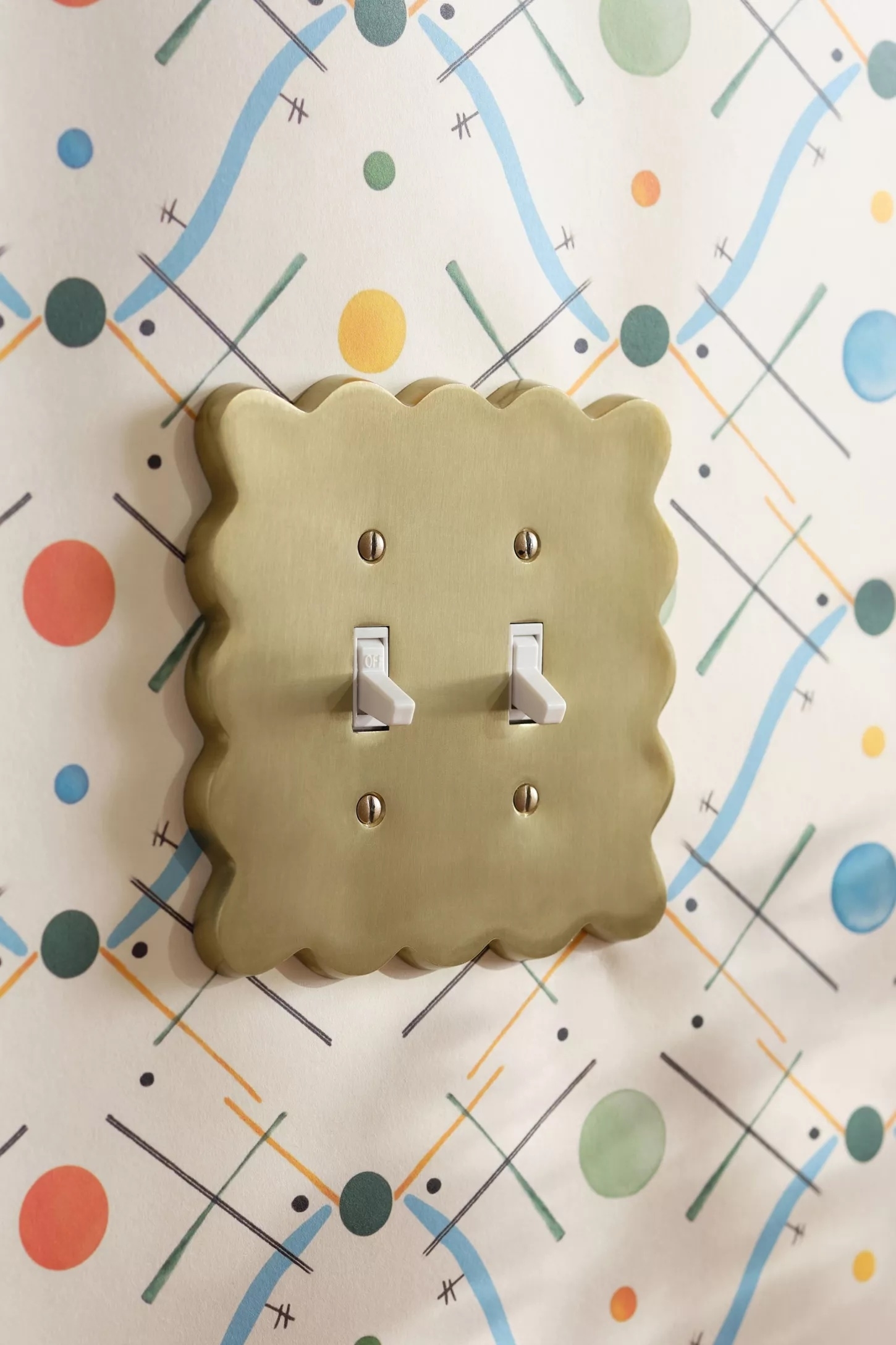 Decorative light switch plate with quirky geometric-patterned wallpaper featuring dots and lines in various directions