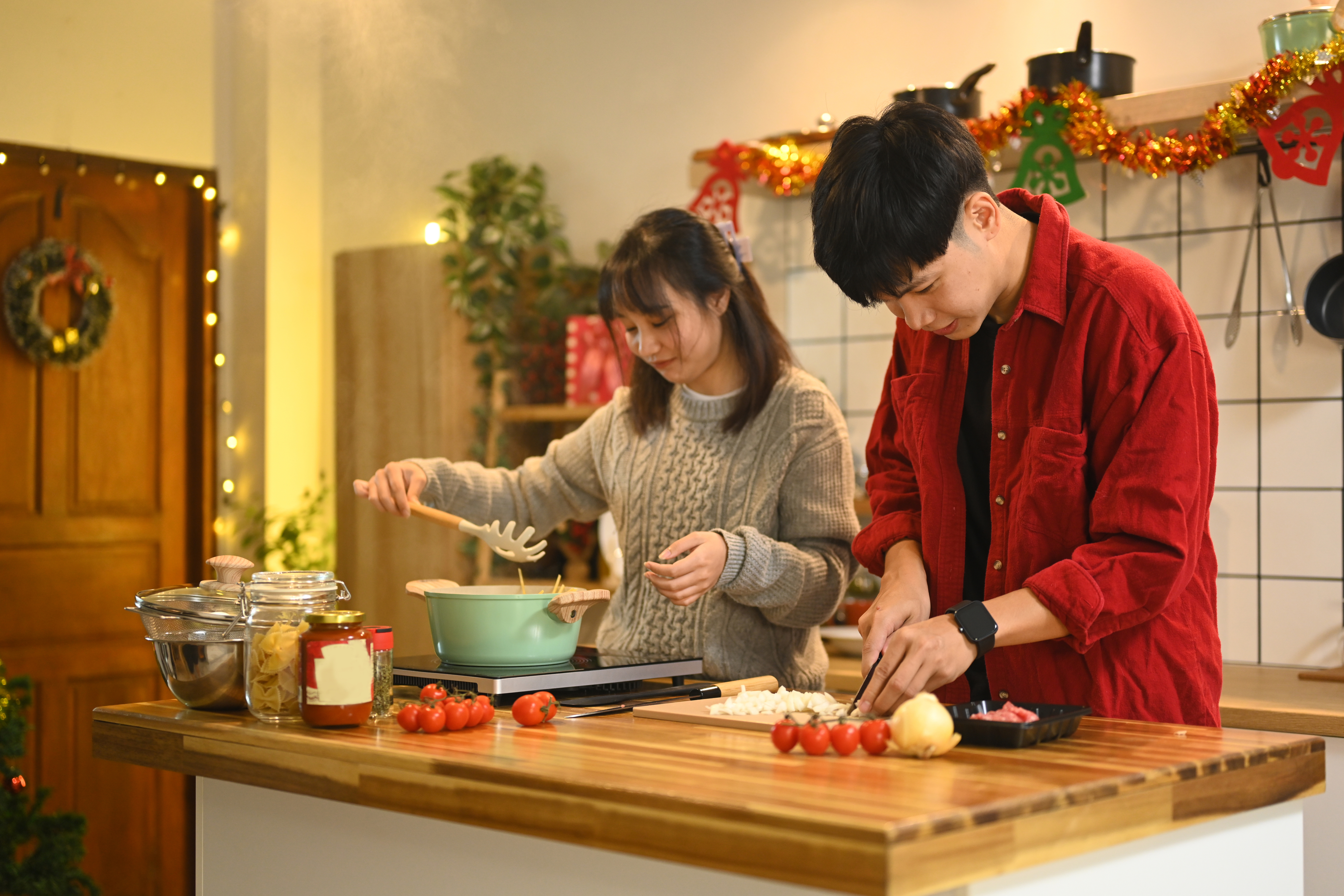 Two people cooking together in a home kitchen, stirring a pot and chopping vegetables, symbolizing teamwork and enjoyment in meal preparation