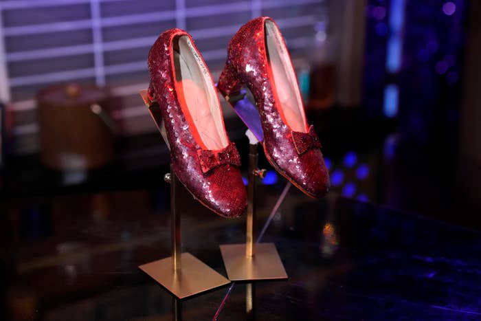 Sequined red shoes with bows displayed on stands indoors