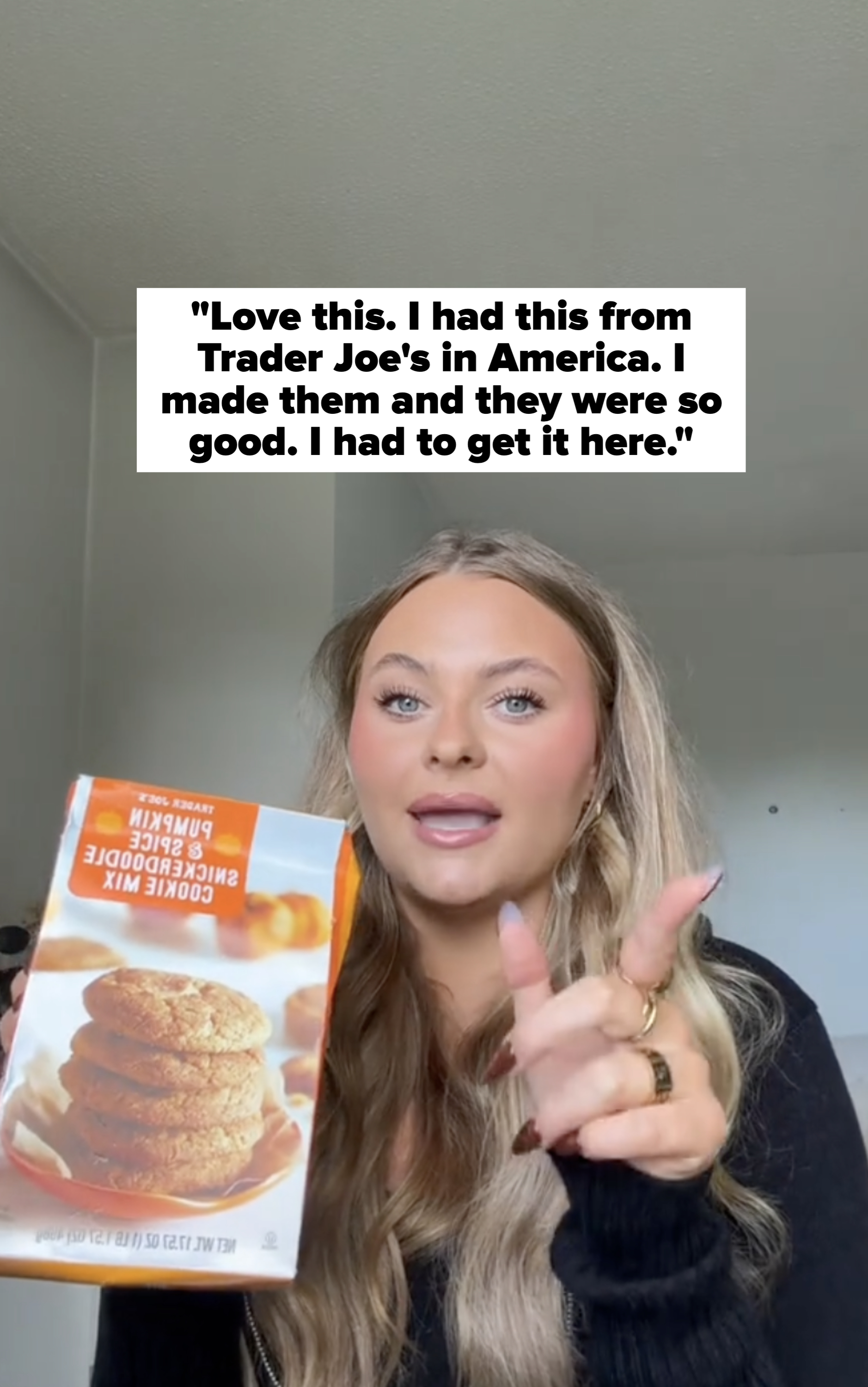 Person holding a box of pumpkin spice cookie mix, speaking energetically on camera