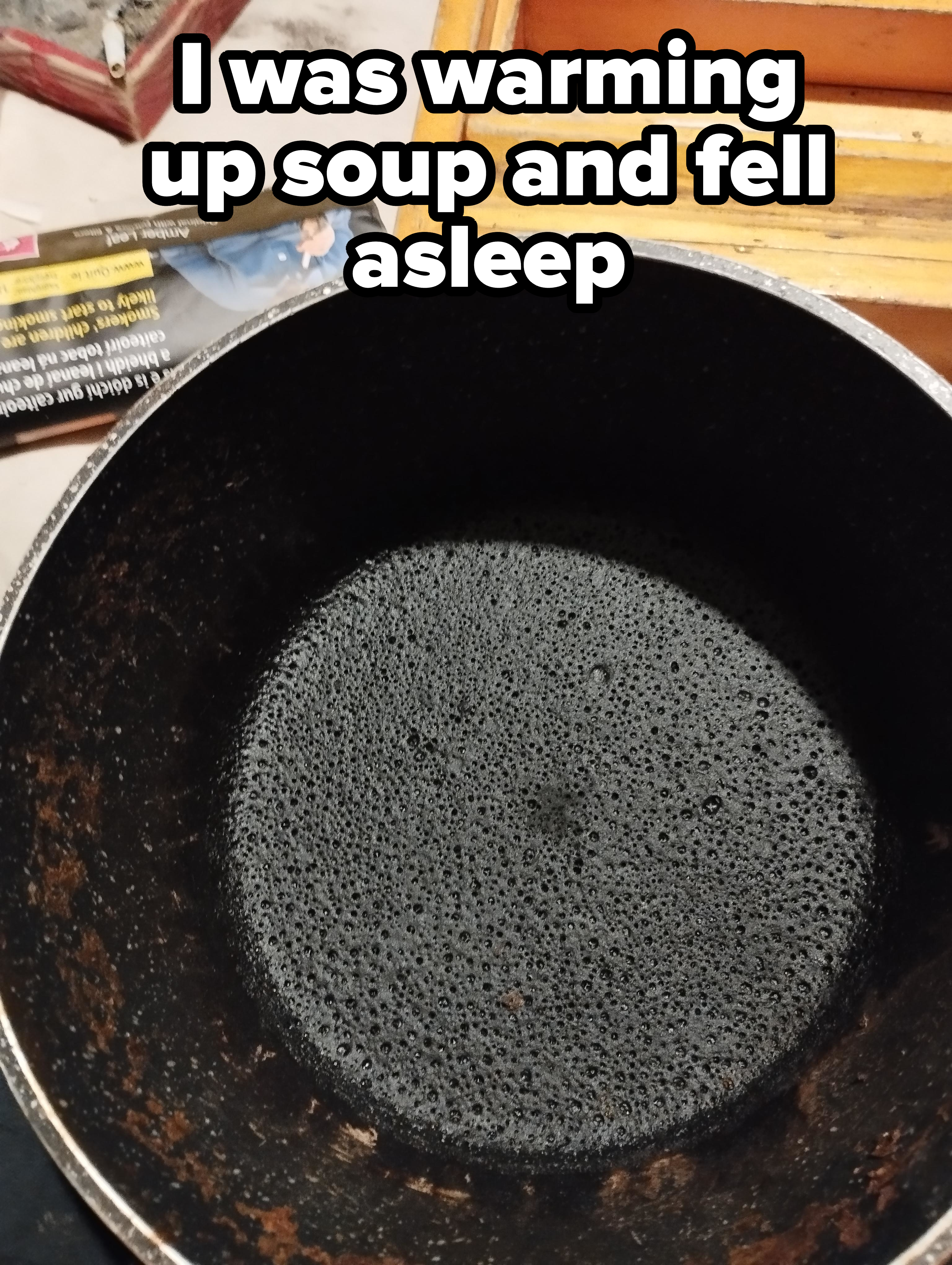 A close-up of a well-used, empty frying pan with a textured surface. Nearby, a partially visible wooden box and magazine